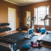 A well-equipped home gym with a variety of exercise equipment. The room has a brown wall and includes a treadmill, an elliptical machine, a stationary bike, a weight bench, and a set of dumbbells neatly arranged on a rack.